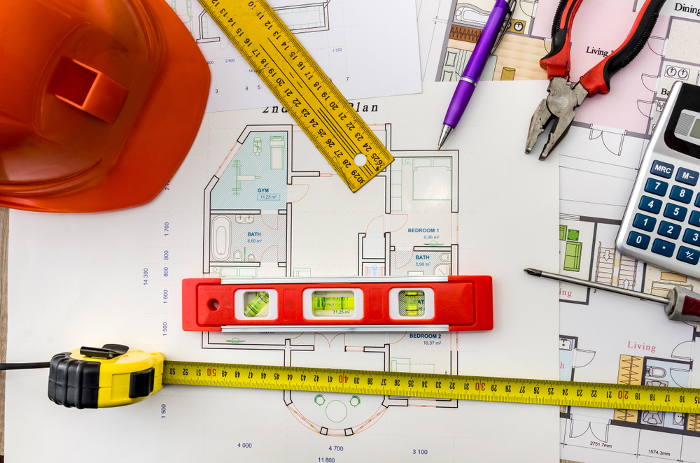 Fix and flip project drawings with a helmet, mason tools on a wood background