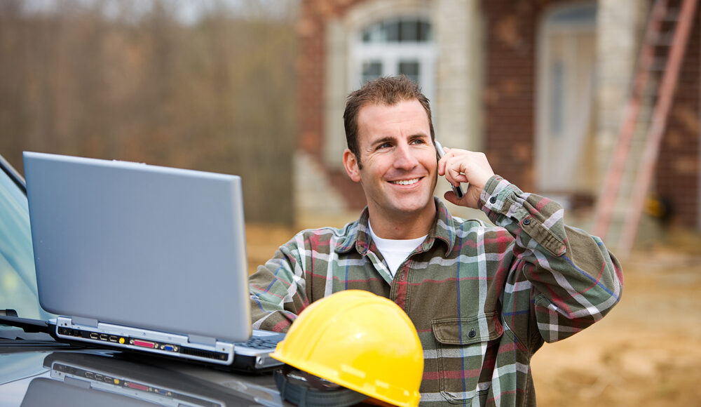 Professional investor using a laptop and phone on-site to manage construction funding