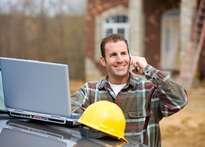 Professional investor using a laptop and phone on-site to manage construction funding
